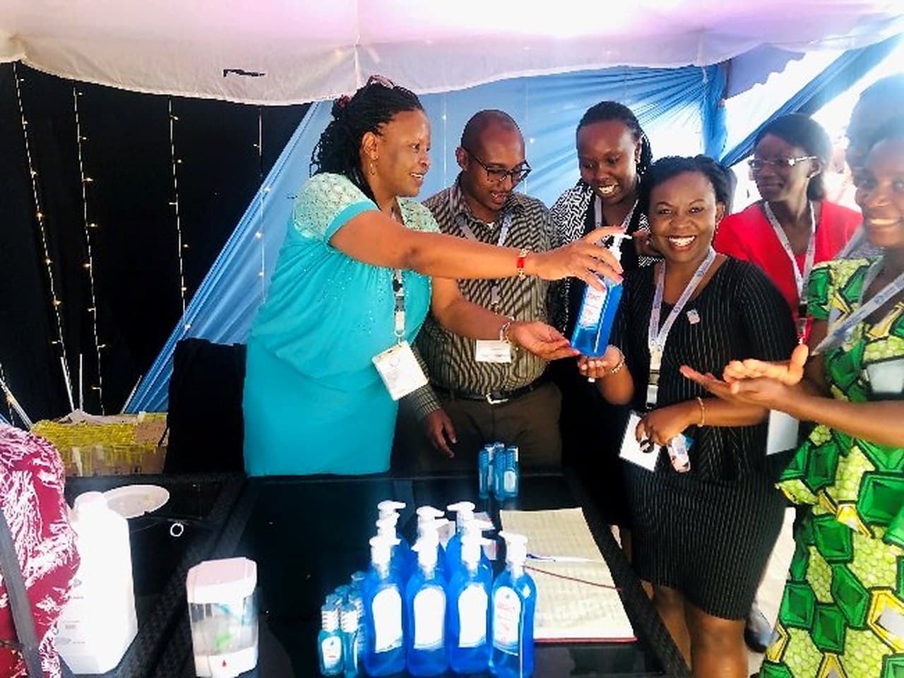 A hand hygiene demonstration at a conference stand with bottles of alcohol-based hand rub.