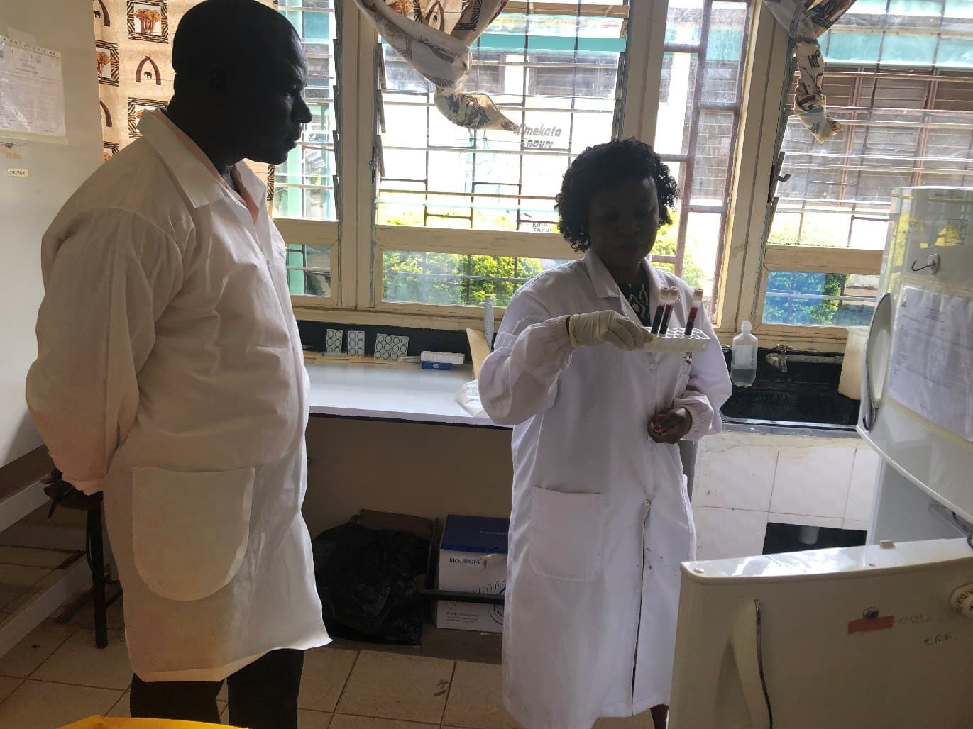 A laboratory worker in a white coat handling specimens during a supervision visit.