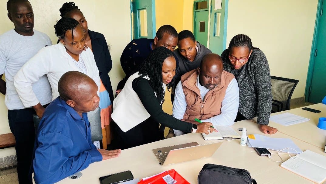 A group of health workers gathered around a desk reviewing documents together.